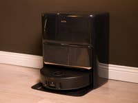 Mova Z60 Ultra Roller Complete, ein schwarzer Roboter-Reiniger vor einer dunklen Wand.