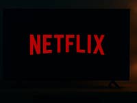 Ein dunkler Raum mit einem Fernseher, der das Netflix-Logo in Rot zeigt.