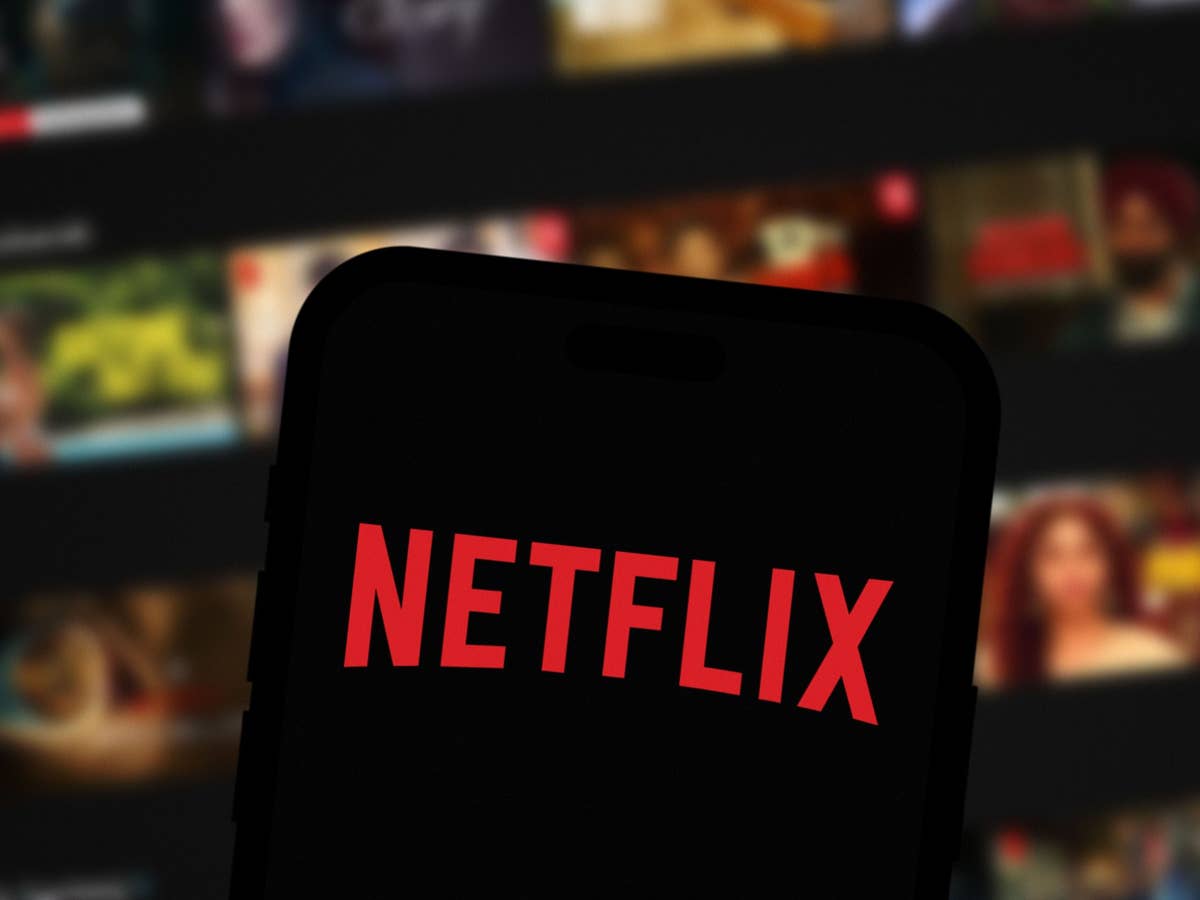 Netflix-Logo auf Smartphone-Display Ein Smartphone zeigt das Netflix-Logo vor einem verschwommenen Hintergrund von Filmtiteln.