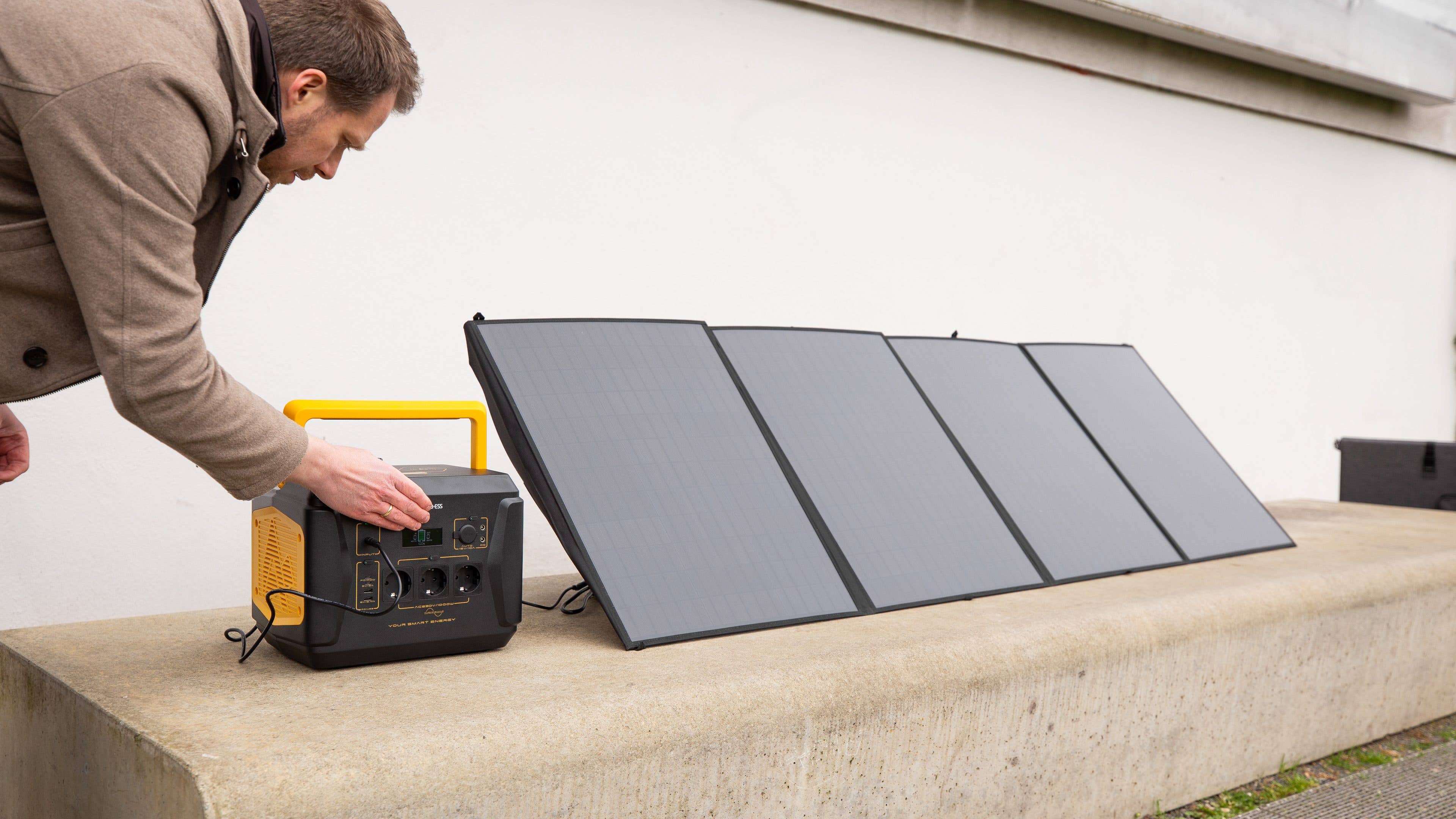 Eine Person schließt ein Solarpanel an eine Powerstation an.