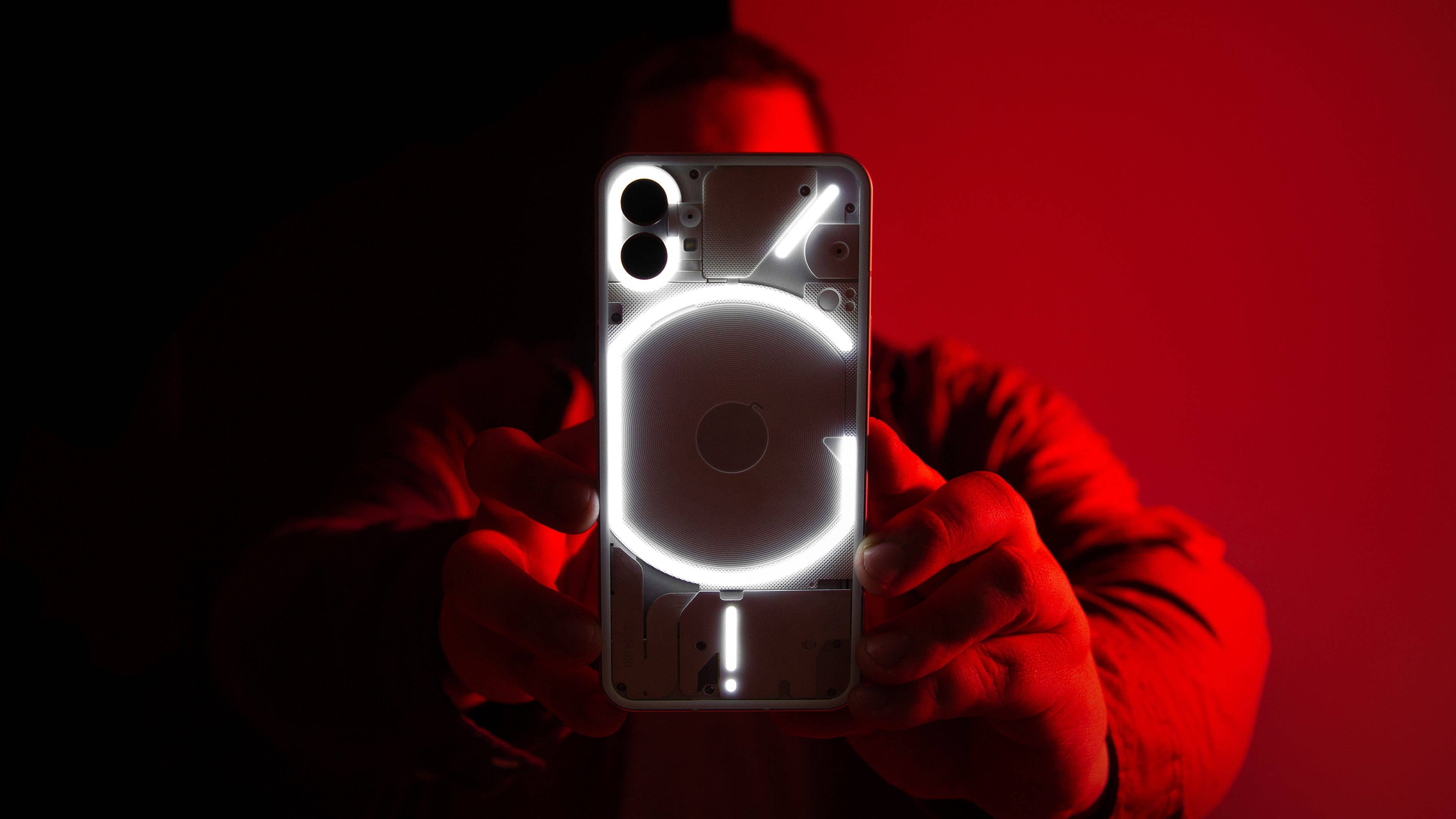 Im Dunkeln kann das Nothing Phone (1) schon spektakulär aussehen. Antoine zeigt im roten Licht stehend die blinkende Rückseite des Nothing Phone (1)
