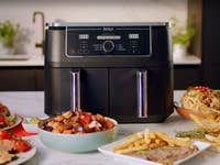 Ninja Heißluftfritteuse auf dem Tisch mit vielen Menüs drumherum