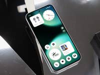 Ein Nothing Phone 2 zeigt eine grüne und schwarze Benutzeroberfläche mit einer Uhr und App-Icons.
