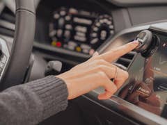 Eine Person drückt den Ooono Verkehrswarner-Knopf auf dem Touchscreen eines Autos.