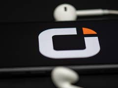 Logo von Otelo auf dem Bildschirm eines Smartphones mit weißen Kopfhörern in der Nähe.