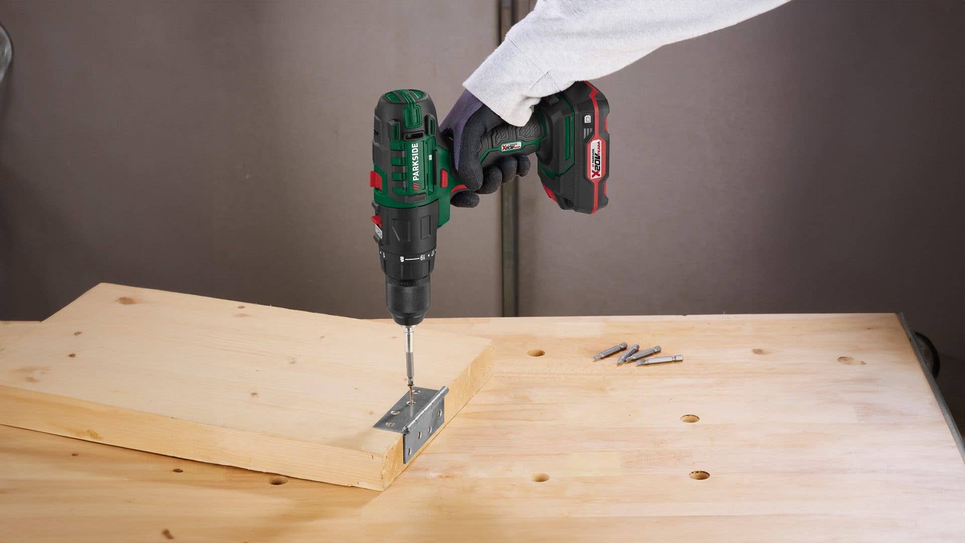 Eine Person, die ein Parkside-Akku-Bohrgerät auf einer Holzoberfläche benutzt.