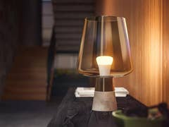 Eine Philips Hue E27 weiß Ambiance Lampe mit Glasschirm auf einem Holztisch in einem modernen Flur.