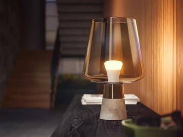 Eine Philips Hue E27 weiß Ambiance Lampe mit Glasschirm auf einem Holztisch in einem modernen Flur.