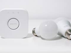 Philips Hue Bridge und zwei weiße Smart-Glühbirnen auf einer weißen Fläche.