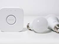 Philips Hue Bridge und zwei weiße Smart-Glühbirnen auf einer weißen Fläche.