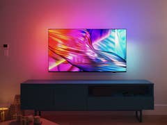 Ein Philips-Fernseher mit lebendigen Farben, an einer Wand über einem modernen TV-Schränkchen in einem gemütlichen Wohnzimmer.