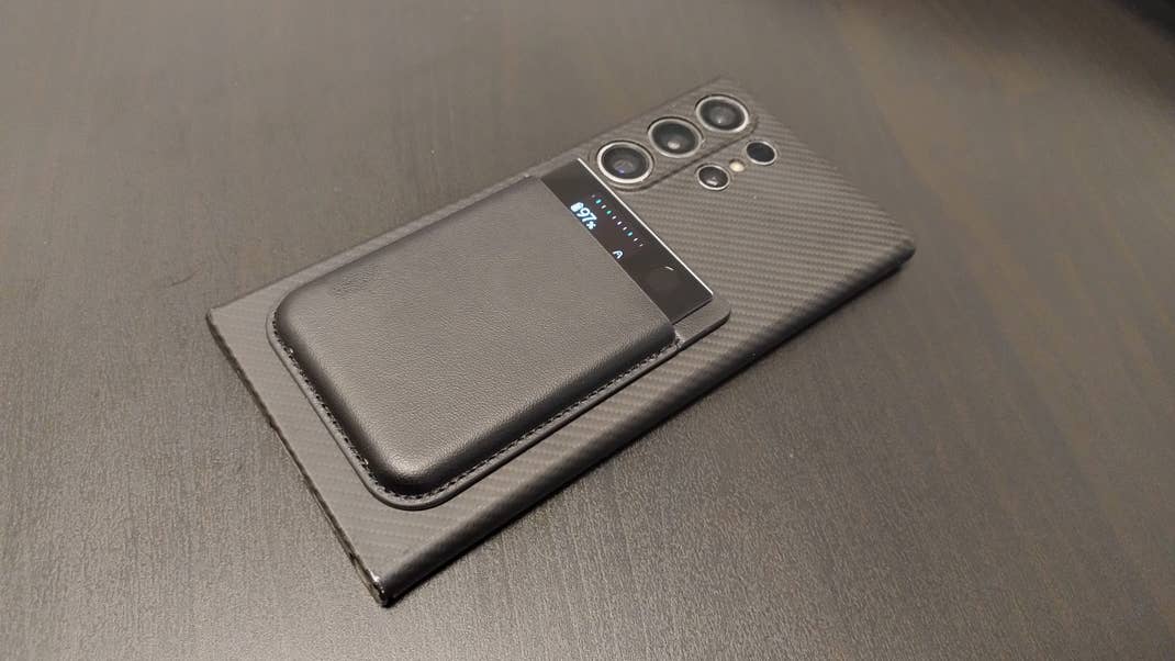 Ein Smartphone mit einer schwarzen Ledertasche auf einer strukturierten Oberfläche. Ein Smartphone mit einer schwarzen Ledertasche auf einer strukturierten Oberfläche.