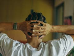 Eine Person mit geflochtenem Haar, die eine Polar Loop trägt, entspannt mit den Händen hinter dem Kopf.