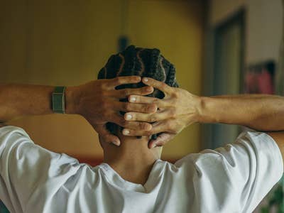 Eine Person mit geflochtenem Haar, die eine Polar Loop trägt, entspannt mit den Händen hinter dem Kopf.