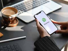 Eine Person, die ein iPhone hält, auf dem WhatsApp läuft.