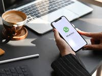 Eine Person, die ein iPhone hält, auf dem WhatsApp läuft.