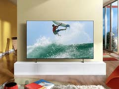 Samsung 4K-TV zeigt einen Surfer, der in einem modernen Wohnzimmer eine Welle reitet.