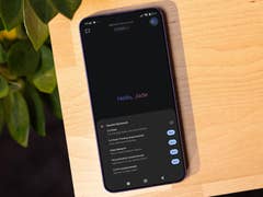 Ein Smartphone zeigt 'Hello_Jade' und Funktionen von 'Gemini Advanced' auf einem Holztisch.