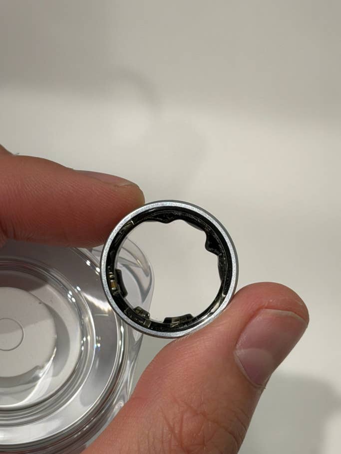 Eine Person hält einen Samsung Galaxy Ring mit einem metallischen Design und einem offenen Inneren.