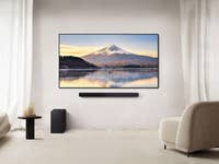 Ein modernes Wohnzimmer mit einer Samsung-Soundbar unter einem Fernseher, der eine Berglandschaft zeigt.