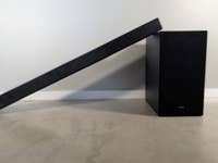 Eine Samsung HW-B540 Soundbar, die schräg neben ihrem Subwoofer auf einer hellen Oberfläche steht.