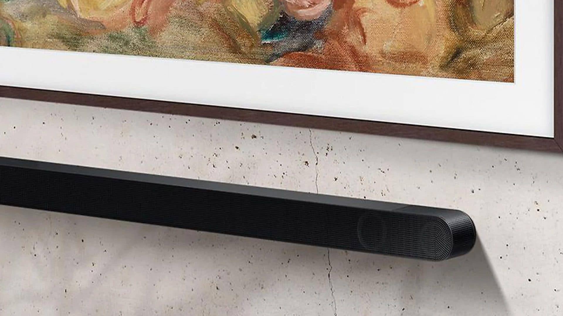 Eine Samsung HW-S810GD Soundbar, die an einer Wand unter einem gerahmten Kunstwerk montiert ist. Eine Samsung HW-S810GD Soundbar, die an einer Wand unter einem gerahmten Kunstwerk montiert ist.