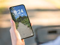 Jemand schaut auf sein Samsung-Handy mit Live-Wetterhintergrund