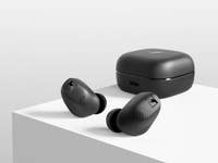 Schwarze Sennheiser Accentum True Wireless-Ohrhörer neben ihrem Ladecase auf einer weißen Oberfläche.