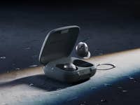 Sennheiser Momentum Sport In-Ear-Kopfhörer in Ladecase auf einer nassen Oberfläche.