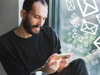 Ein Mann schaut auf ein imaginäres Handy mit zu viel eingehenden Nachrichten