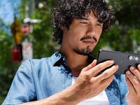 Ein Mann mit lockigem Haar, der im Freien ein Sony Xperia 1 VII Smartphone benutzt.