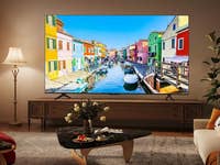 Ein TCL-Fernseher, der einen malerischen Kanal mit bunten Gebäuden in einem Wohnzimmer zeigt.