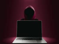 Ein Laptop im Vordergrund mit rot-schwarzem Hintergrund.