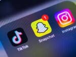 Ein Smartphone-Bildschirm zeigt soziale Medien-App-Symbole: TikTok, Snapchat und Instagram.