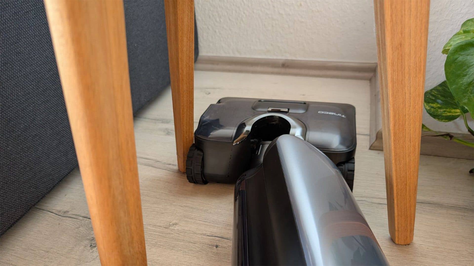 Ein Tineco Floor One S9 Artist Staubsauger unter einem Holztisch.