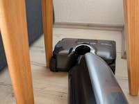 Ein Tineco Floor One S9 Artist Staubsauger unter einem Holztisch.