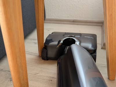 Ein Tineco Floor One S9 Artist Staubsauger unter einem Holztisch.