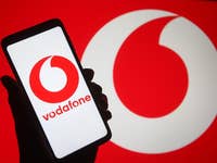 Vodafone-Logo auf einem Smartphone mit großem Logo im Hintergrund.