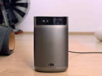 Ein tragbarer XGIMI Mogo 2 Pro Projektor auf einem Holzfußboden mit einer schwarzen Matte in der Nähe.