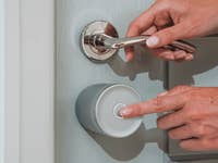 Eine Person verwendet ein Yale Linus Smart Lock L2 Lite an einer Tür und drückt einen Knopf.