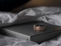 Helio Ring liegt auf einem Buch, das auf einem Bett liegt.