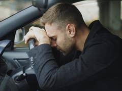 Autofahrer liegt mit dem Kopf auf dem Lenkrad