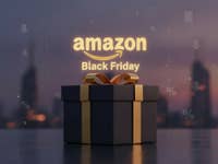 Schwarzes Geschenk vor einer Stadtkulisse. Darüber sieht man das Amazon-Logo und einen 