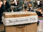 Ein Amazon-Paket in einem Fitnessstudio und einem Schweißband auf dem steht "Neujahresvorsatz 2026".