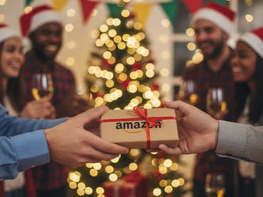 Personen feiern eine Weihnachtsfeier. Im Vordergrund wird ein Päckchen mit Amazon-Logo überreicht.