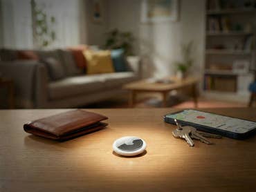 Ein Apple AirTag liegt auf einem Tisch und wird von einem Licht beleuchtet.