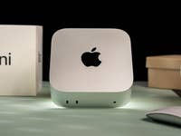 Apple Mac Mini M4 2024 auf einer Oberfläche mit einer Maus und Kisten im Hintergrund.