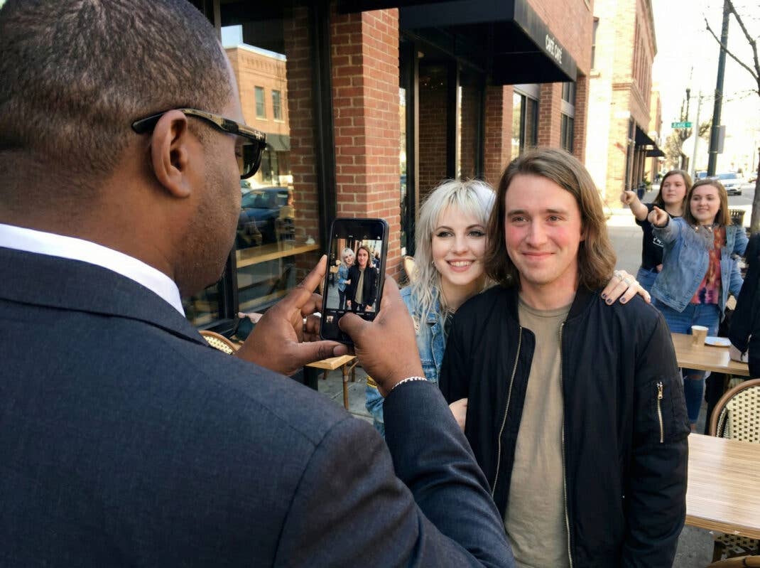 Ein Bodyguard macht ein Selfie von einer Sängerin und ihrem Fan.
