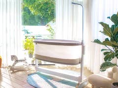 Ein modernes Babybett von Bosch in einem hellen Raum mit großen Fenstern, Pflanzen und einem gemütlichen Stuhl.