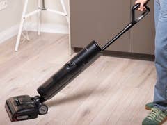 Eine Person verwendet einen Dreame H15 Pro Staubsauger auf einem Holzboden.